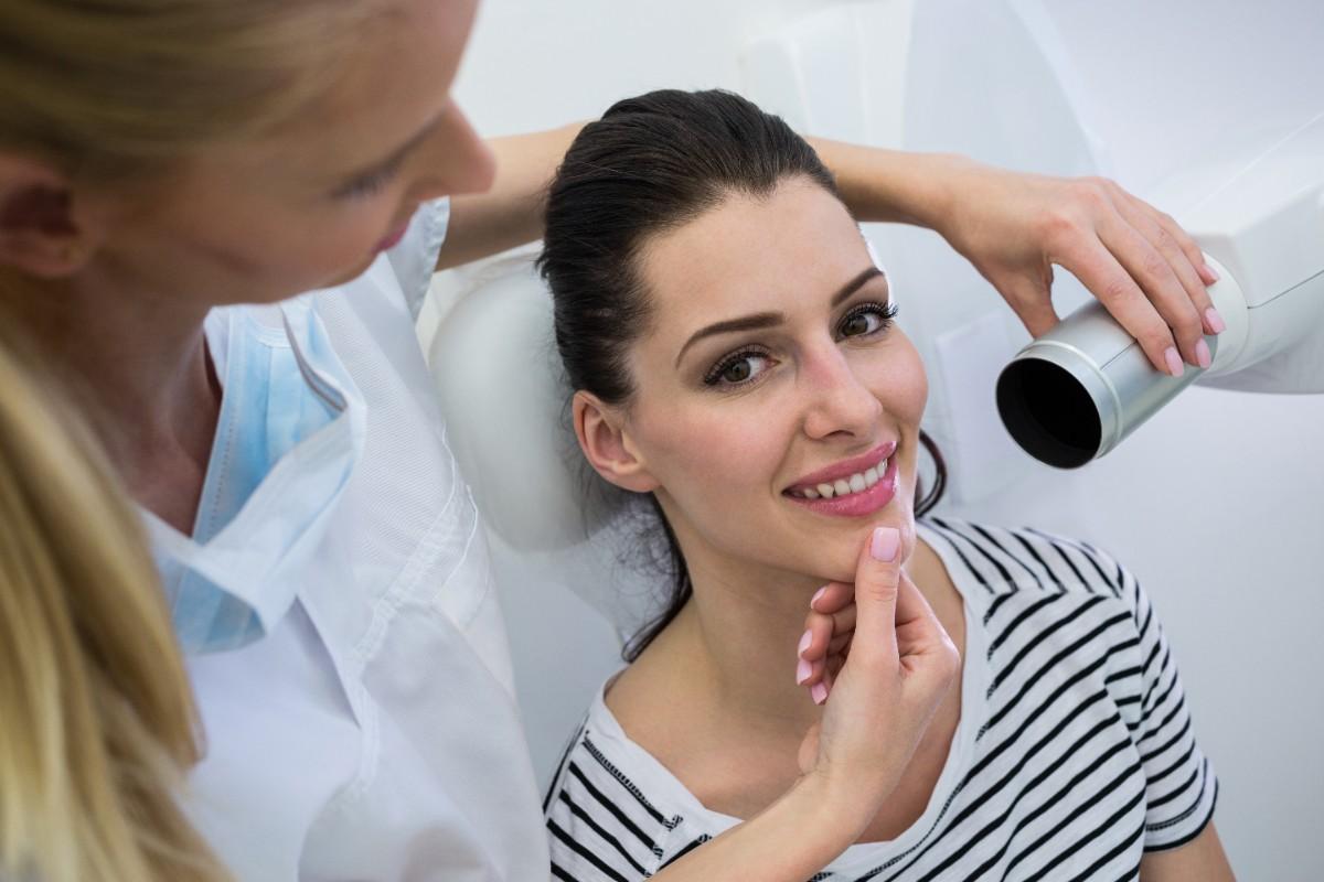 Dentist explaining dental crown treatment with tooth model to patient