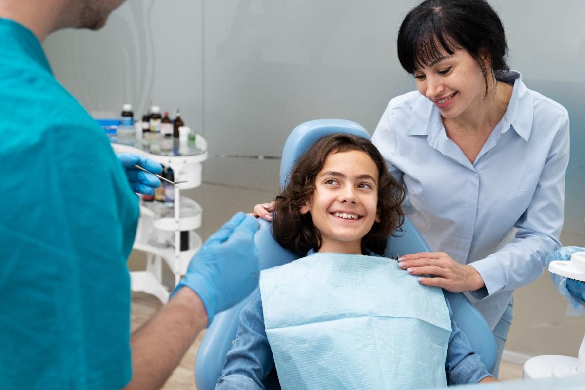 Child smiling during dental checkup with parent nearby